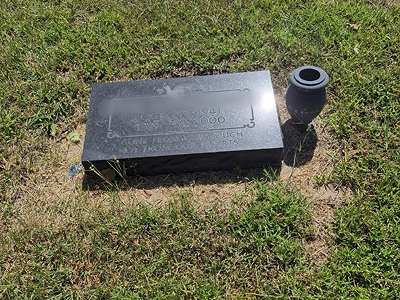 Flat granite grave marker with vase — before cleaning
